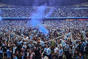 Fans invading a football pitch during a match, highlighting the excitement and controversy of pitch invasions in modern football.